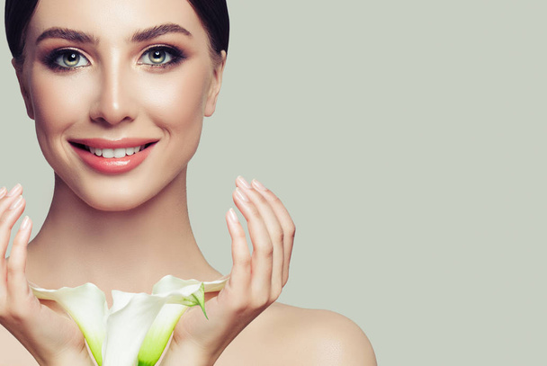 Kadın yüzü portre. Kadın sağlıklı ciltle manikürlü eller ve beyaz çiçekler. Yüz tedavi, kozmetik ve spa - Fotoğraf, Görsel