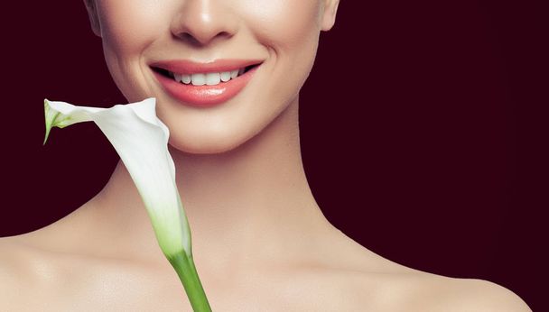 Söpö naisten kasvojen lähikuva. Hymyile valkoiset hampaat ja kukka
 - Valokuva, kuva