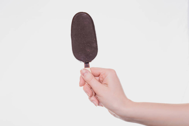 Detail fotografie chutné mňam lahodné sladké cukroví s čokoládový obal zmrzliny v ženské ruce izolovaných na bílém pozadí místa kopie copyspace perforací - Fotografie, Obrázek