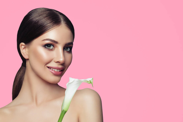 Wellness-Frau Modell mit gesunder Haut und weißen Blumen auf rosa Hintergrund mit Kopierraum. Gesichtsbehandlung, Kosmetologie und Wellness - Foto, Bild