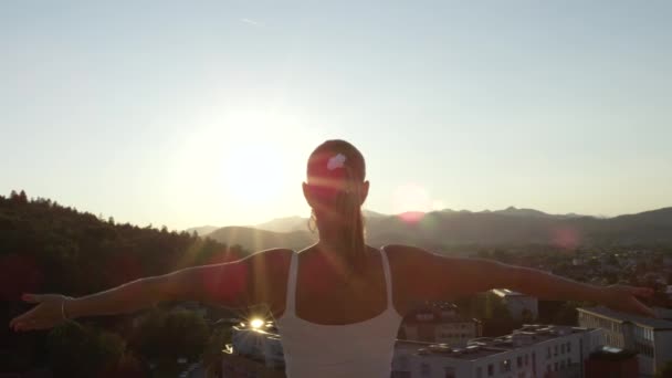 Zpomalený pohyb, Close Up: Pretty woman osvětlena sluncem, stojící na vrcholu mrakodrapu, díval se na budovy a lidé zvyšování rukou, pocit silné a při kontrole jako Všemocný Bůh - Záběry, video