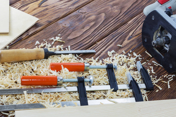 Η σύνθεση του κλιπ, σμίλες, και τσιπ στην επιφάνεια εργασίας στο εργαστήριο ξύλινων. - Φωτογραφία, εικόνα