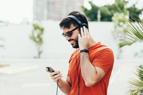 Ο άνθρωπος ακούει μουσική με το smartphone του πάνω στο δρόμο - Φωτογραφία, εικόνα