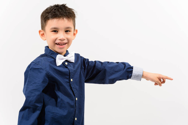 Студийный снимок милого счастливого мальчика, улыбающегося и указывающего пальцем на Сида
 - Фото, изображение