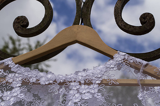 wedding dress - wedding dress hanging on hook with blue sky background- wrought iron - Photo, Image