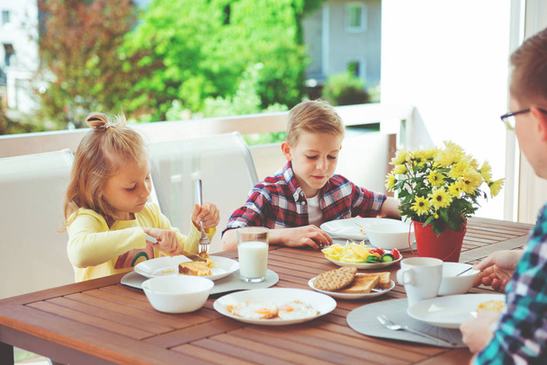Happy young family having fun during breakfast on the big terrasse at home  - Foto, Imagen