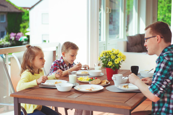 Happy young family having fun during breakfast on the big terrasse at home  - Фото, зображення