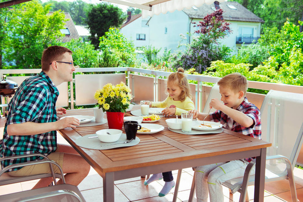 Happy young family having fun during breakfast on the big terrasse at home  - Fotografie, Obrázek