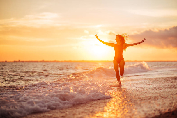 carefree woman dancing in the sunset on the beach. vacation vitality healthy living concept - Foto, Imagem