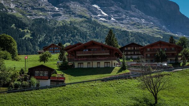 Chalets traditionnels en bois dans la pittoresque ville suisse de Grindelwald en été devant la face nord de la montagne Eiger entourée de verdoyants pâturages
 - Photo, image