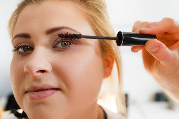 Visage, beauty concept. Closeup portrait of woman face getting her eye eyelashes makeup done by professional artist using mascara - Φωτογραφία, εικόνα