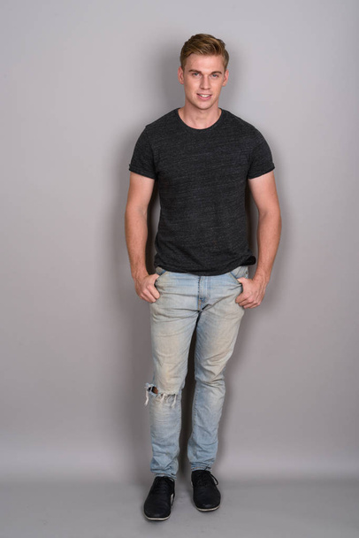 Jovem homem bonito com cabelo loiro vestindo camisa cinza contra gr
 - Foto, Imagem