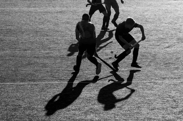 Silueta. La sombra de un jugador de hockey corre con un palo de hockey en un campo de hockey
. - Foto, Imagen