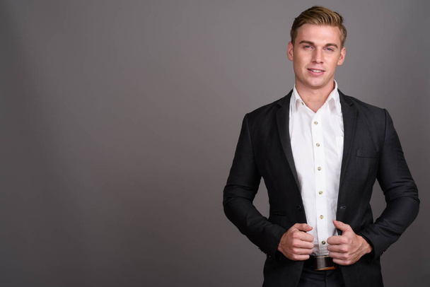 Young handsome businessman with blond hair wearing suit against  - Photo, image