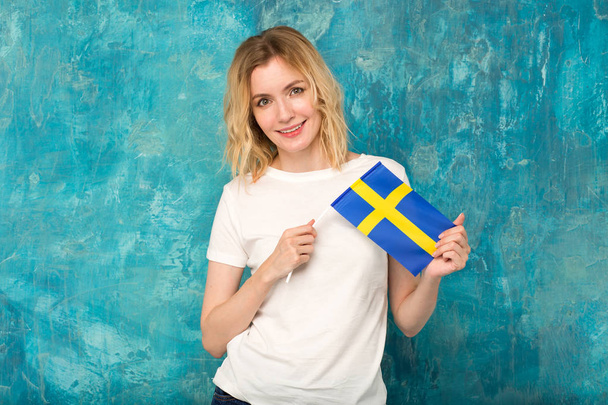 Beautiful blonde woman with the flag of Sweden in hands. Scandinavian. - Foto, immagini