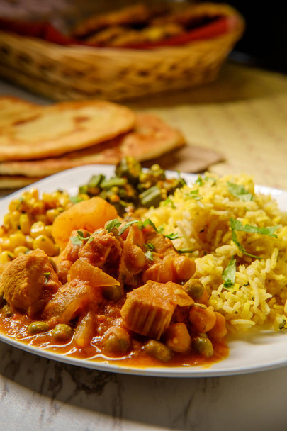 Indiase kip curry groente diner met gebakken okra biryani rijst en maïs  - Foto, afbeelding