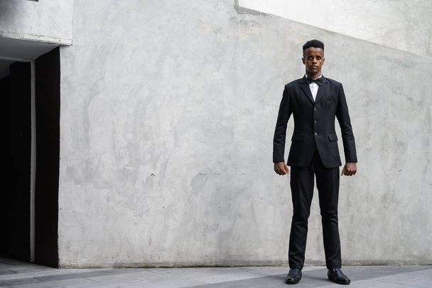 屋外コンクリート壁にスーツを着ている若いハンサムなアフリカの実業家の肖像画 - 写真・画像