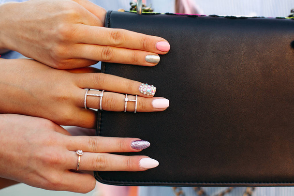 Dívky ukazující její stylovou manikúru, drží Petr prsty na černé kabelky. - Fotografie, Obrázek