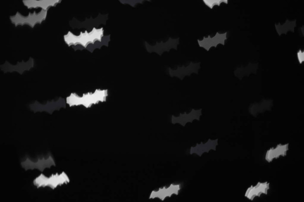 defocused white bats silhouette ghosts on black for halloween background - holidays, decoration and party concept - Фото, зображення