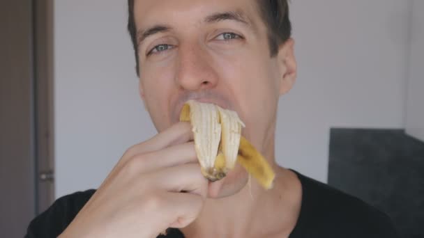 Крупним планом молодий чоловік їсть банан вдома на кухні
 - Кадри, відео