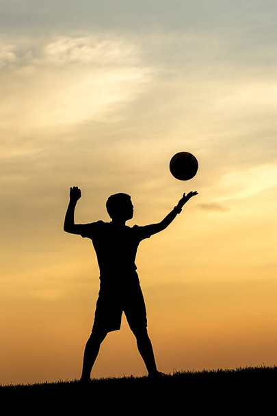 Concepto foto de un joven atleta silueta poniéndose apetecible para servir a un voleibol
. - Foto, imagen