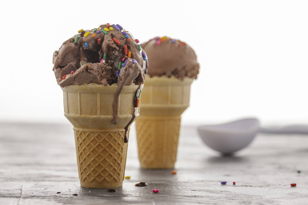 A close up of a chocolate ice cream cone with chocolate syrup and sprinkles. - Photo, Image