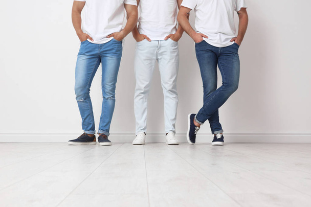 Group of young men in jeans near light wall - Fotoğraf, Görsel