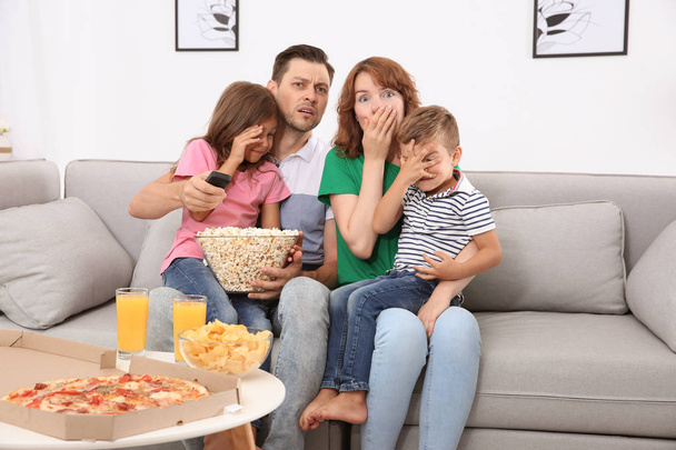 Family watching TV with popcorn in room - Foto, imagen
