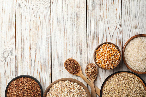 Flat lay composition with different types of grains and cereals on wooden background - Foto, imagen