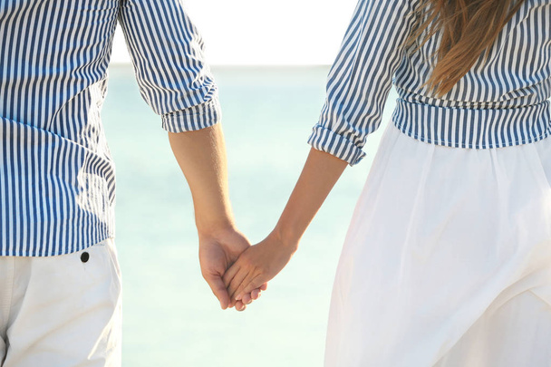 Happy young couple holding hands on beach, closeup - Fotoğraf, Görsel