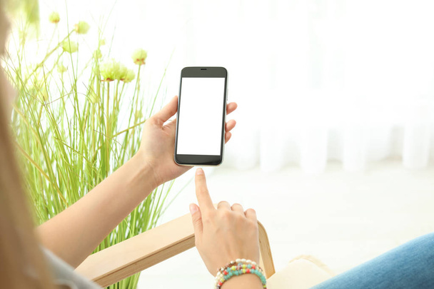 Woman holding smartphone with blank screen on blurred background. Mockup for design - Foto, Imagen