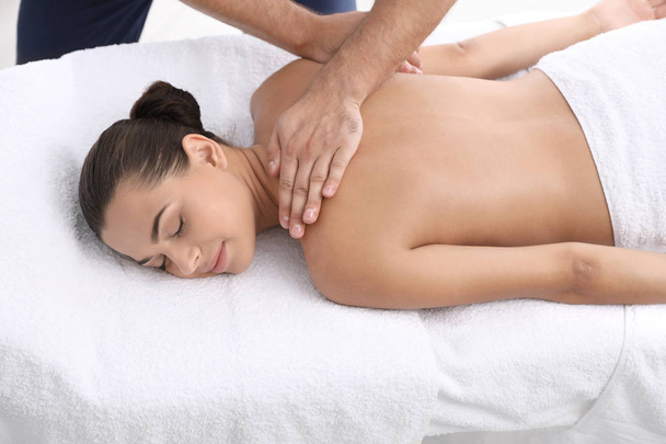 Relaxed woman receiving back massage in wellness center - 写真・画像