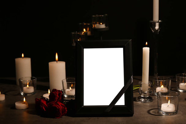 Empty frame with black ribbon, candles and roses on table. Funeral symbol - Fotó, kép