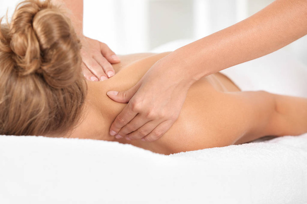 Relaxed woman receiving shoulders massage in wellness center - Foto, afbeelding