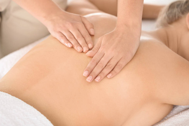 Расслабленная женщина получает массаж спины в оздоровительном центре
 - Фото, изображение