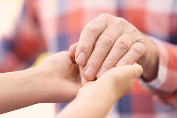 Young woman holding elderly man hand, closeup. Help service - Photo, Image
