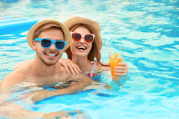 Young couple in pool on sunny day - Φωτογραφία, εικόνα