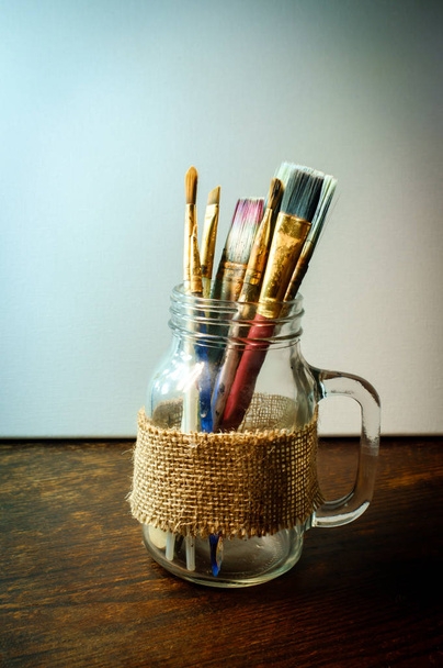 Mason Jar of assorted stained old artist paintbrushes - Photo, Image