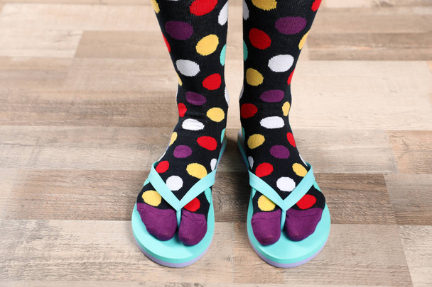 Woman wearing bright socks with flip-flops standing on floor - Foto, Imagem
