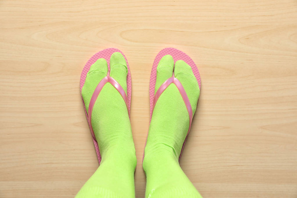 Woman wearing bright socks with flip-flops standing on floor, top view - Foto, Imagem