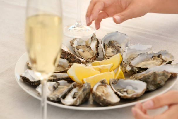 Woman with fresh oysters at table, focus on hands - Foto, immagini