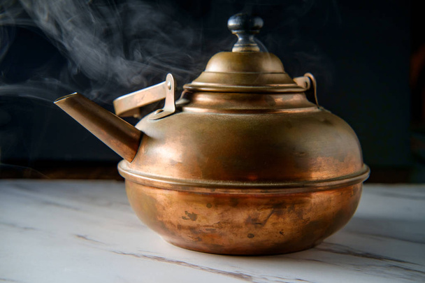 Σφυρίζοντας ζεστό τσάι κατσαρόλα στον πάγκο της κουζίνας με ατμό από βραστό νερό - Φωτογραφία, εικόνα