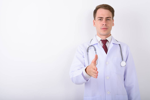 junger schöner Mann Arzt vor weißem Hintergrund - Foto, Bild