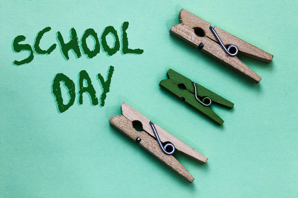 Text sign showing School Day. Conceptual photo starts from seven or eight am to three pm get taught there Three brown green vintage clothespins clear background Holding things - Photo, Image