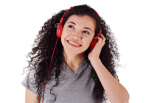 Young beautiful woman listening to music indoor. Isolated white background. - Photo, image