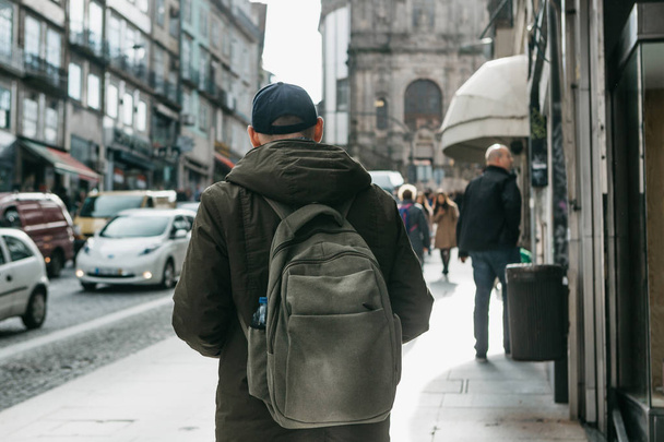 A tourist with a backpack walks down the street in Porto in Portugal. Travel around Portugal - Fotoğraf, Görsel