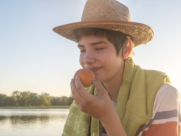 lähikuva nuori mies tuoksuva persikka hedelmiä valmis purra sitä rannalla kopioi tilaa
 - Valokuva, kuva