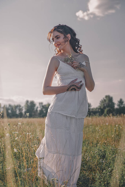 Adult woman in white dress walking on meadow. - Foto, afbeelding
