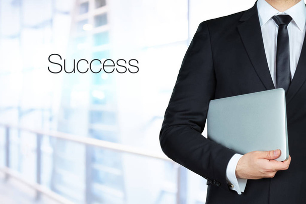 Close up of businessman hands holding laptop and standing near text Success - Fotó, kép