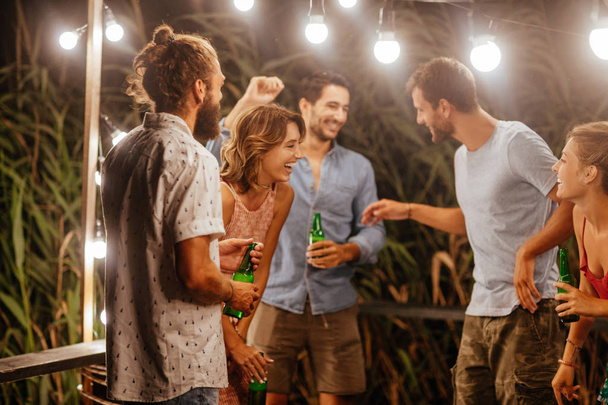 Group of young men and women laughing at at outdoor summer party. - Фото, изображение